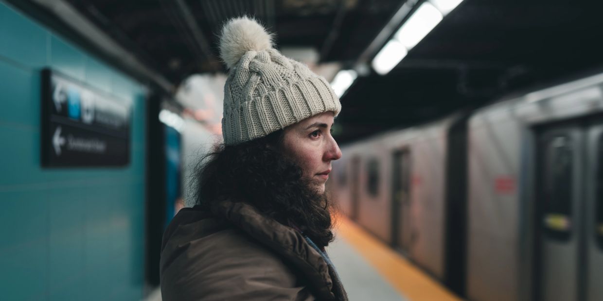 Woman in a winter hat waiting at a subway station.