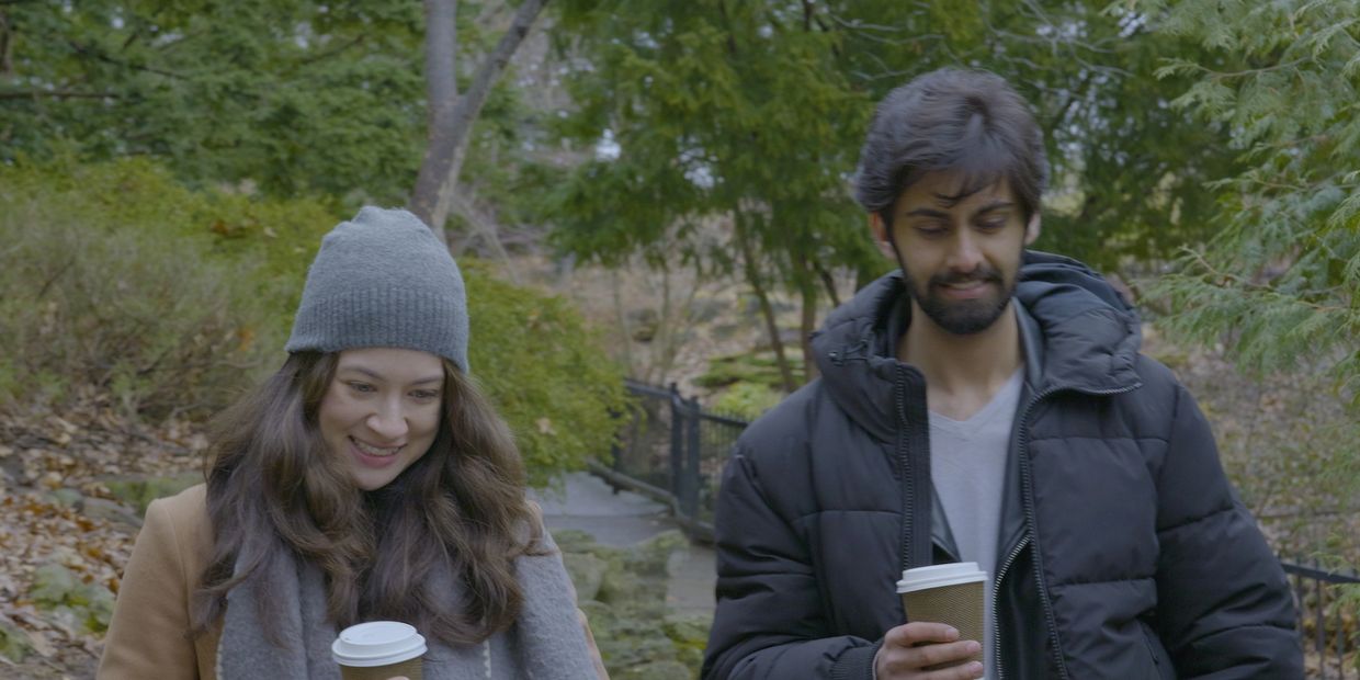 Two friends enjoying coffee outdoors in a park.