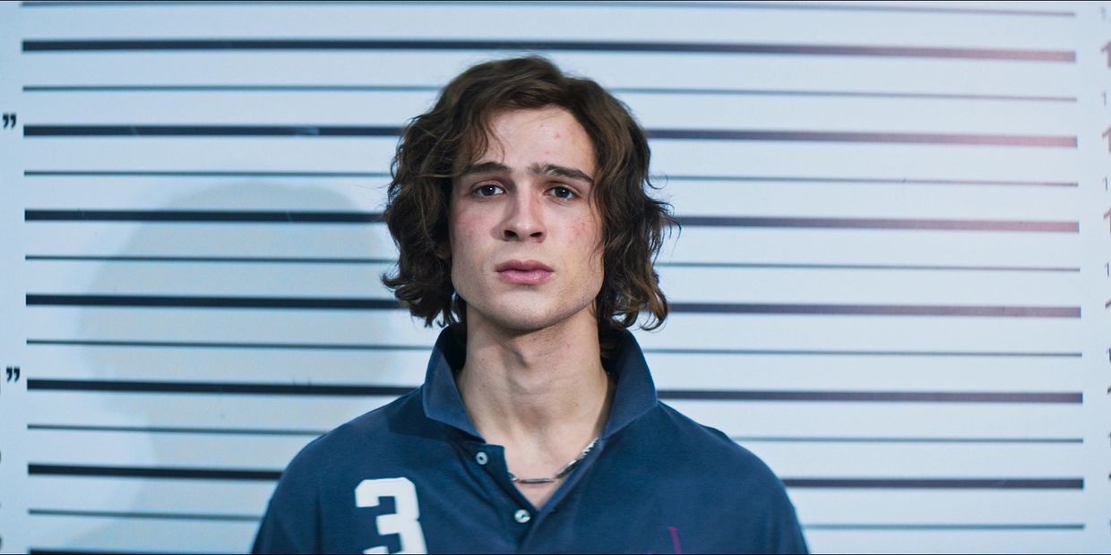 Young man standing against height measurement backdrop.