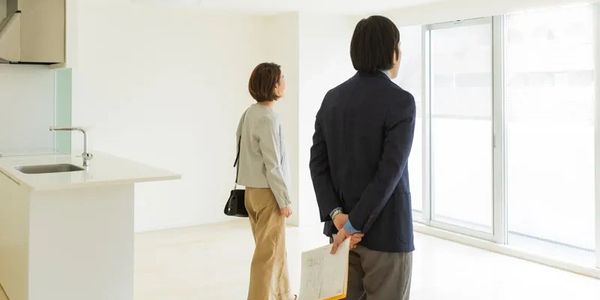 Couple inspecting a bright, empty apartment with large windows.