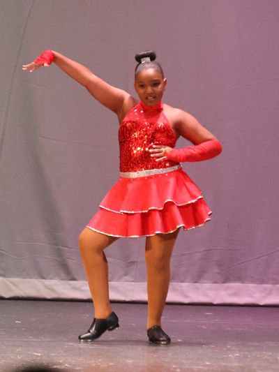 Young dancer in a sparkly red costume striking a pose on stage.