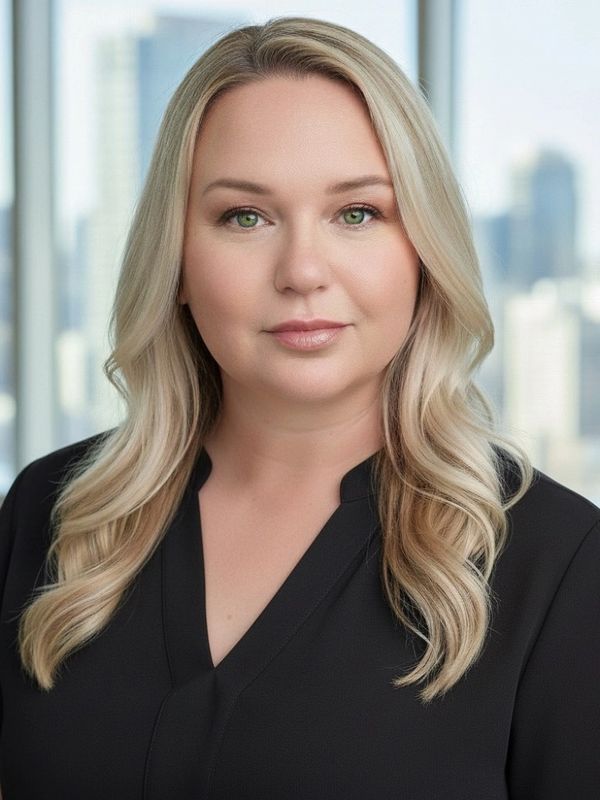 Professional woman with blonde hair and green eyes in a black top.