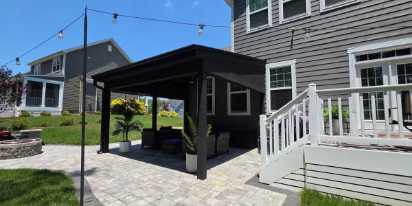 Gray paver patio backyard with black shed roof cover and outdoor furniture.