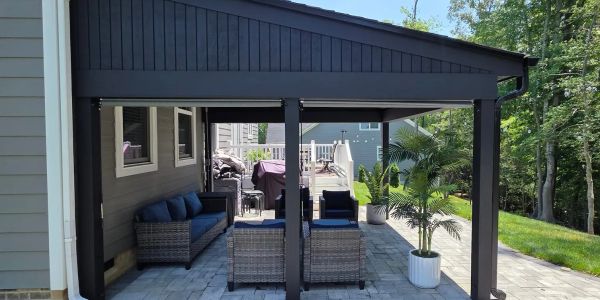 Gray paver patio backyard with black shed roof cover and outdoor furniture.
