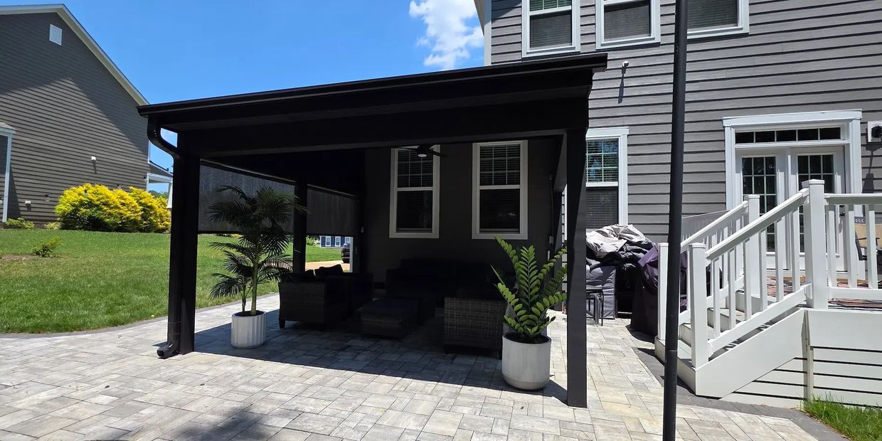 Gray paver patio backyard with black shed roof cover and outdoor furniture.