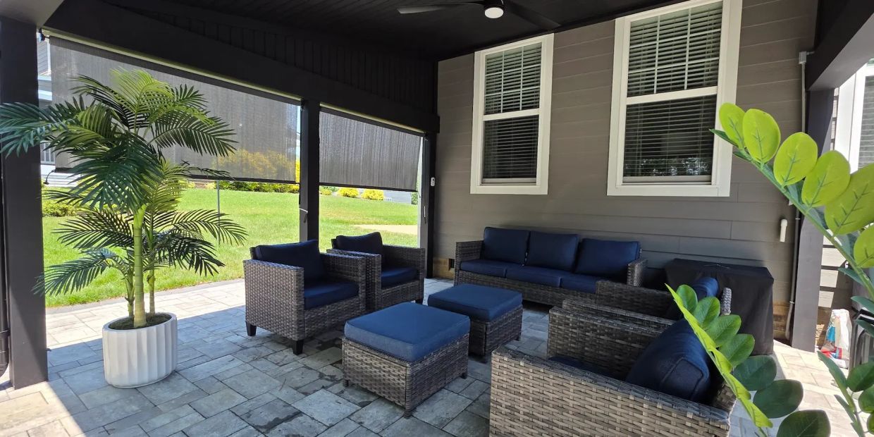 Gray paver patio backyard with black shed roof cover and outdoor furniture.