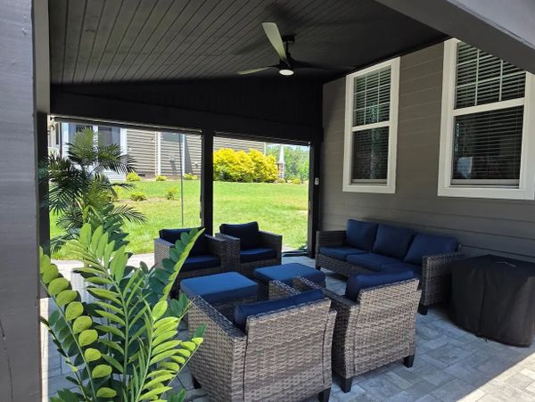 Gray paver patio backyard with black shed roof cover and outdoor furniture.
