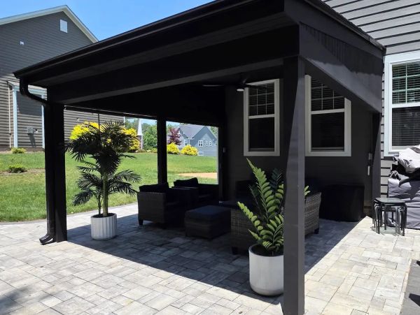 Gray paver patio backyard with black shed roof cover and outdoor furniture.