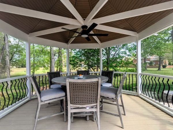 Outdoor dining table in gazebo with custom railings, outdoor fan, & PVC decking. 