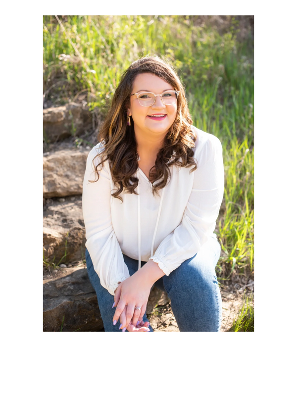 Keslie sits on stone steps outdoors smiling