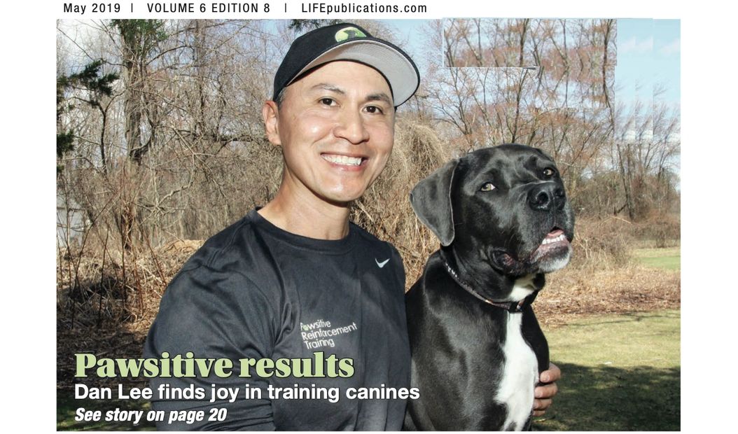 Dan Lee smiles while training a large black and white dog outdoors.