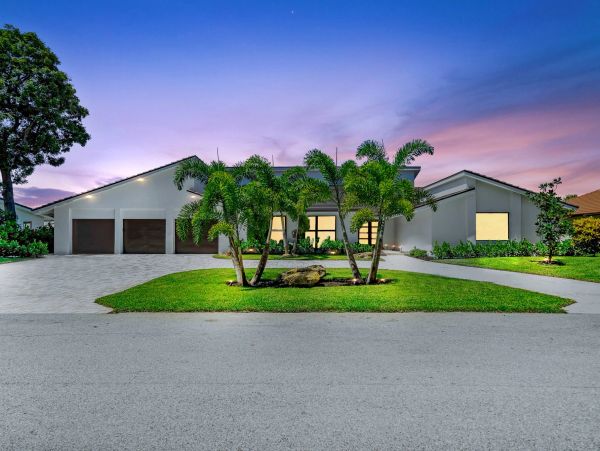 Modern single-story house with palm trees and a three-car garage at sunset.