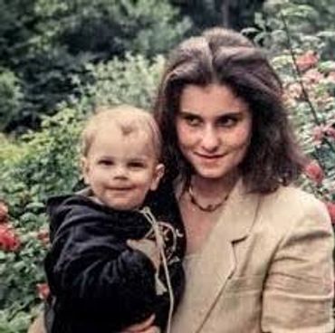 Woman holding a smiling baby outdoors.