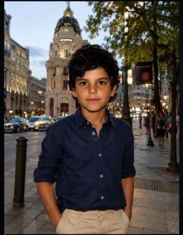 Boy standing on a city street at dusk.