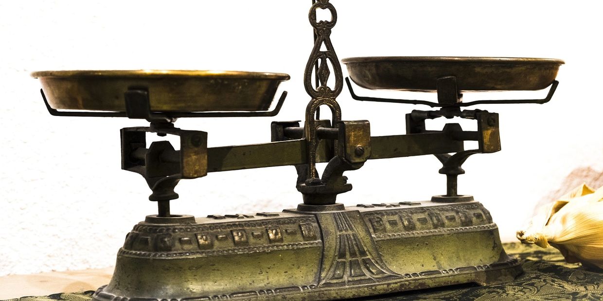 An antique brass balance scale with two empty pans.