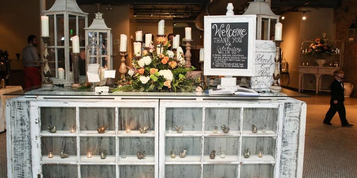 Rustic wedding welcome table with candles, flowers, and sign.