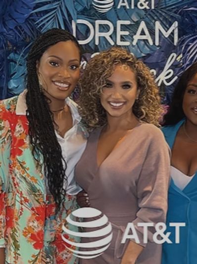 Three women smiling at an AT&amp;T event with a tropical-themed backdrop.
