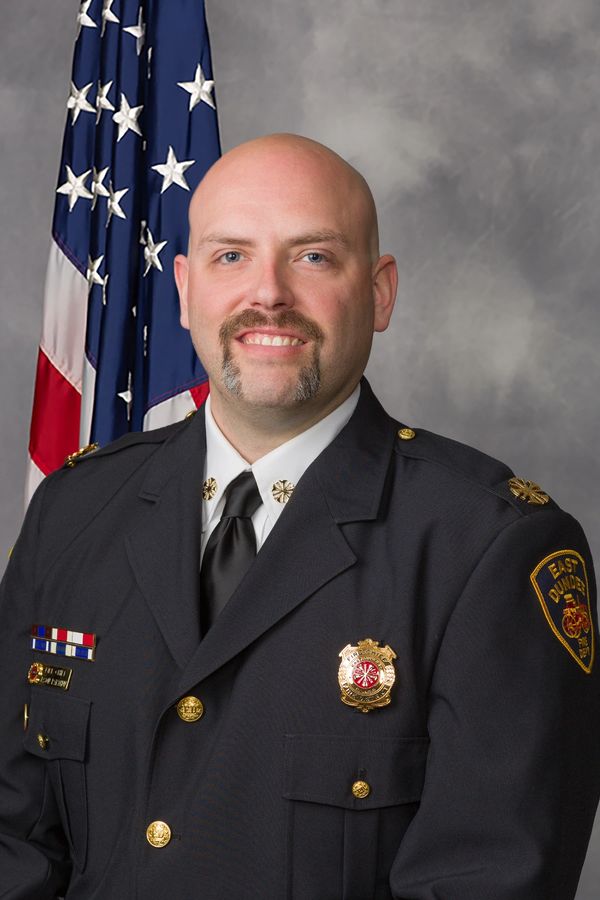 Portrait of a firefighter in uniform with an American flag background.