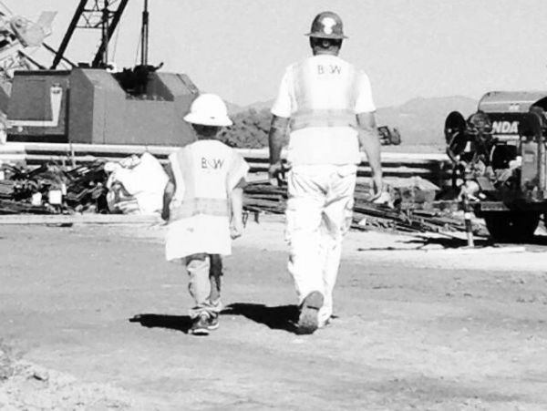 Adult and child in construction gear at a worksite.