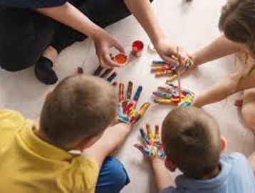 Children painting hands with colorful paints.