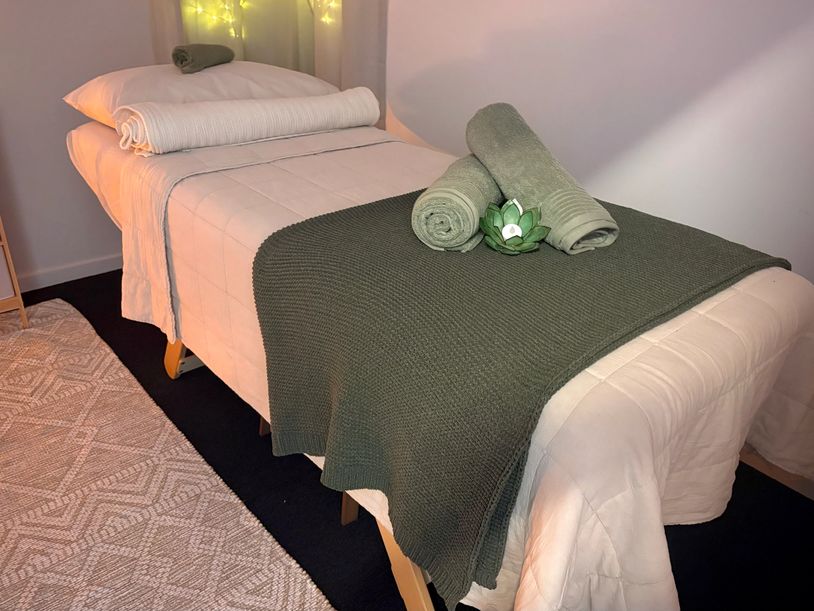 Cozy spa treatment bed with rolled towels and soft lighting.