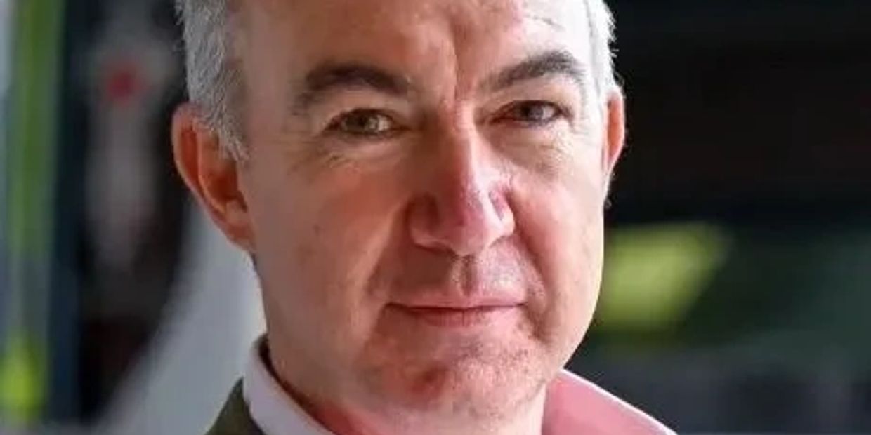 Confident middle-aged man in a blazer and pink shirt.