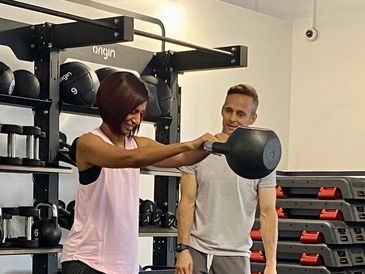 Trainer John instructing a client in kettlebell swings.