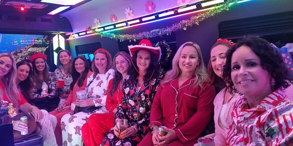 Group of women in festive pajamas celebrating inside a decorated vehicle.