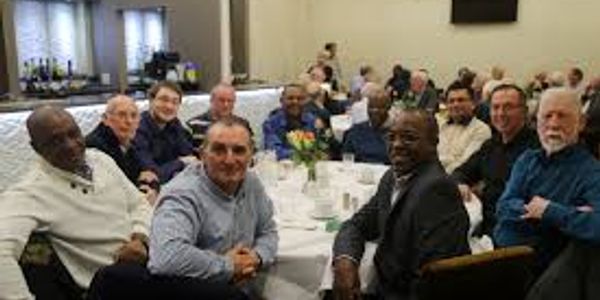 Group of men sitting around a table at an event.