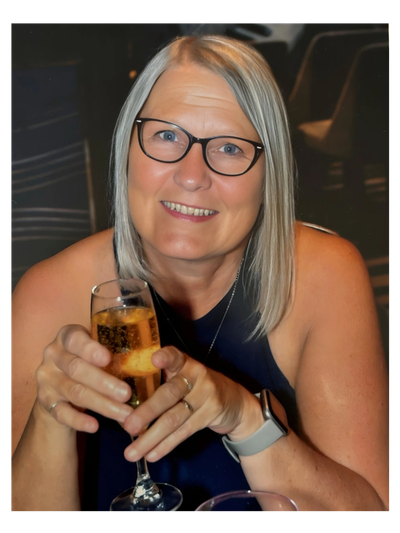 Dawn Booth Life Coach smiling and holding a glass of champagne.