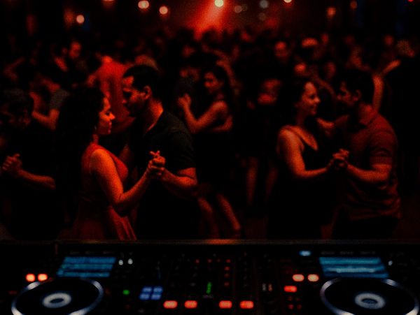 Couples dancing closely in a dimly lit club with DJ equipment in the foreground.