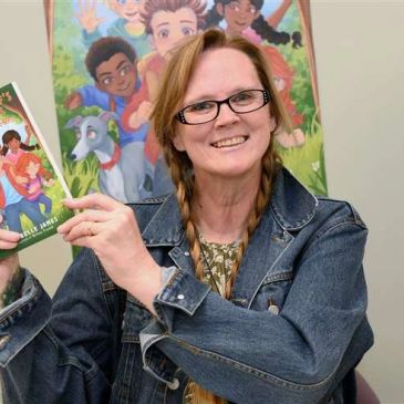 Woman holding a children's book and smiling.