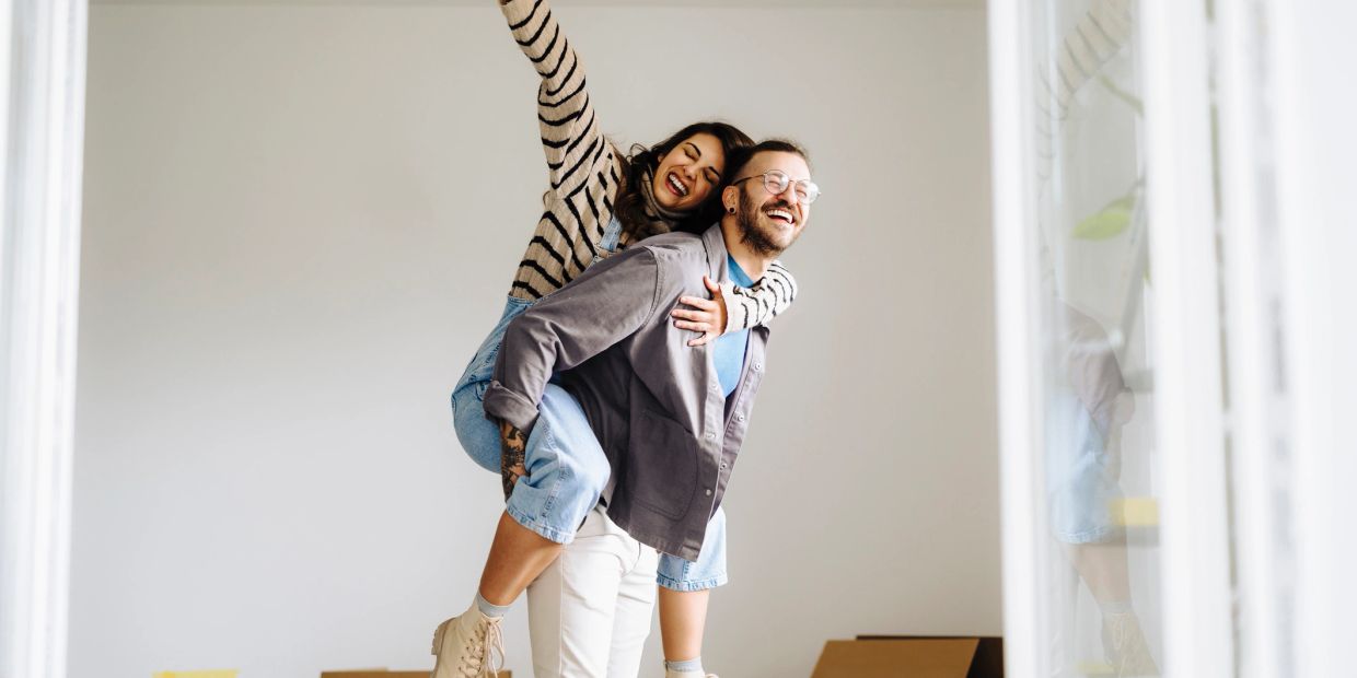 Couple having fun with a piggyback inside a home.