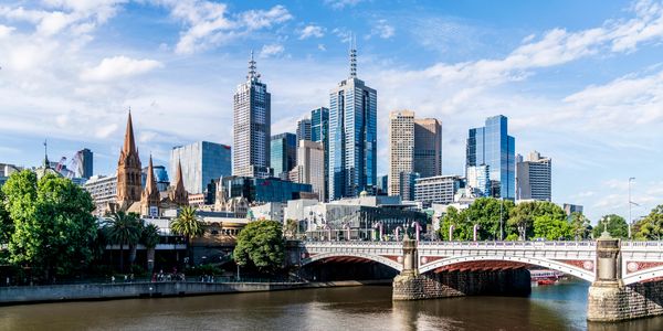 City skyline with a river and bridge under a blue sky.
