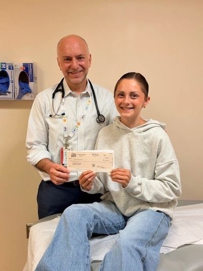 Ella hands Dr. Dome with Children’s National Hospital in Washington, D.C a check for $20,000.00.