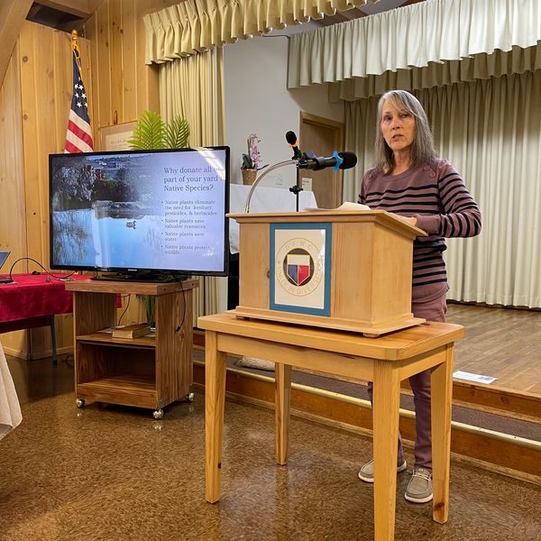 Woman giving a presentation about native plants at a podium indoors.