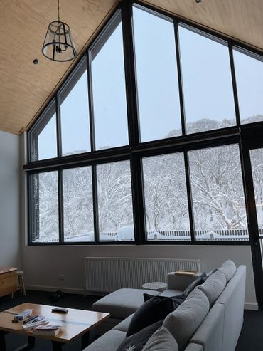 Modern living room with large windows showcasing a snowy winter landscape.
