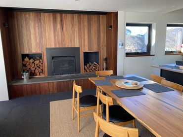 Cozy dining area with wooden table and fireplace.