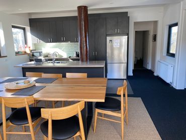 Modern kitchen and dining area with wooden furniture and dark cabinetry.