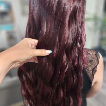 Hand holding wavy maroon hair.
