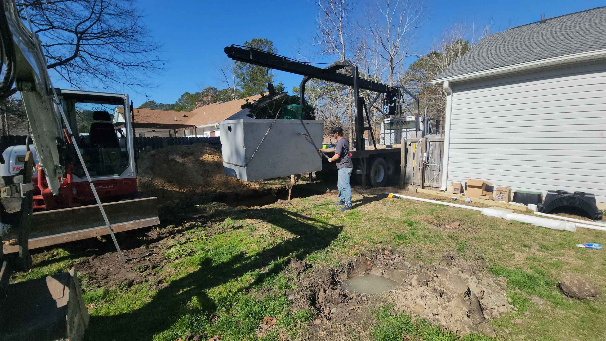 Wyatt guiding septic tank into the hole.