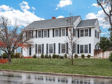 White two-story house with black shutters and a well-kept lawn.