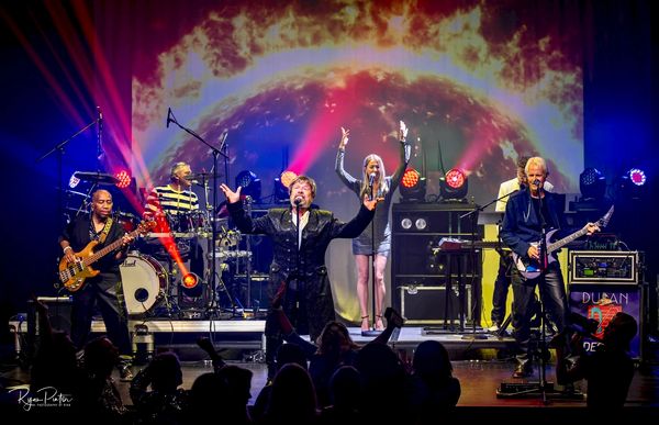 Energetic band performing live on stage with vibrant lighting and enthusiastic crowd.