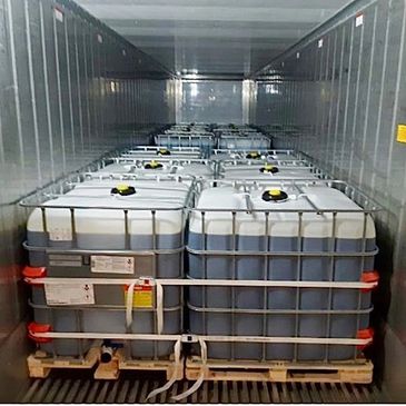 Two large industrial liquid containers outside a warehouse.