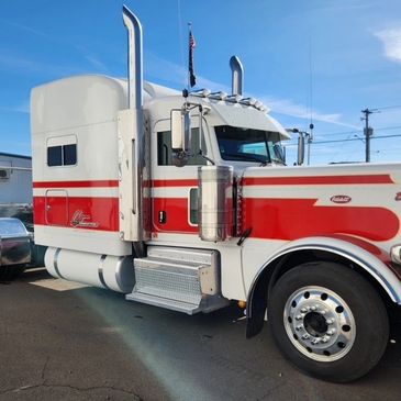Classic white and red Peterbilt semi-truck parked under a clear blue sky.