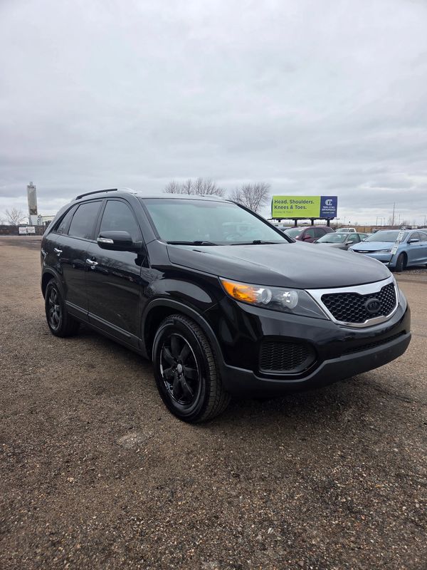 Black SUV parked on a gravel lot under a cloudy sky.