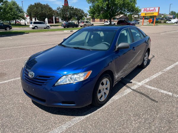 Blue Toyota sedan parked in a sunny parking lot near a Michaels store.