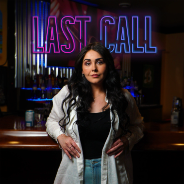 A woman stands confidently in front of a neon 'LAST CALL' sign inside a bar.