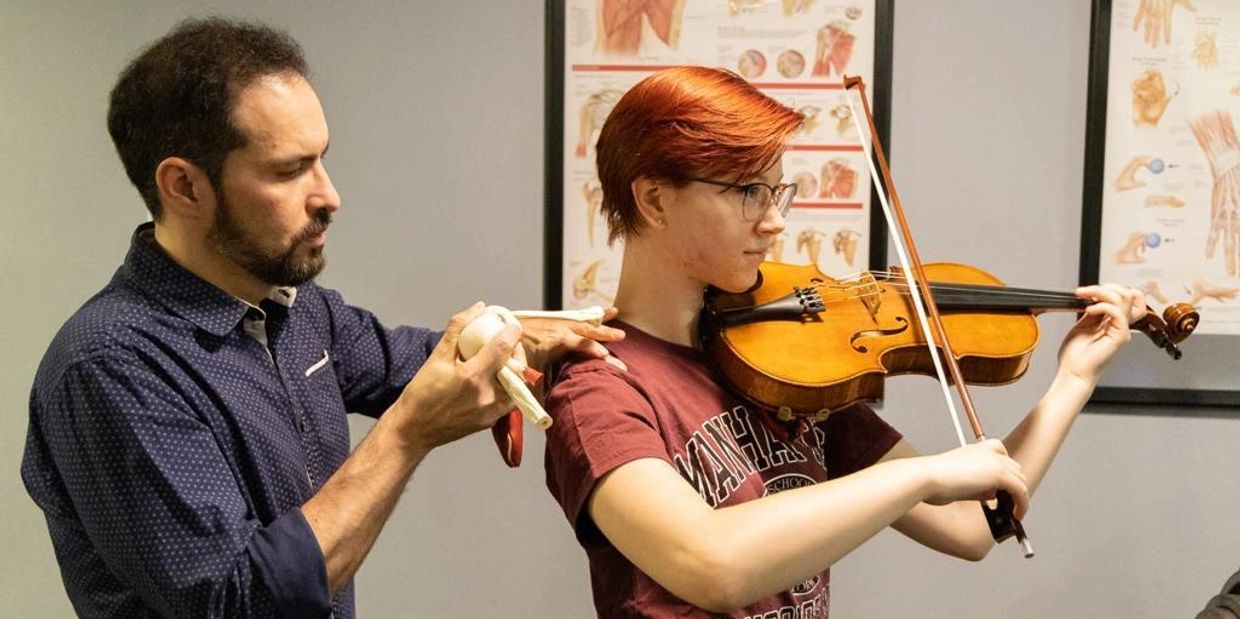 Doctor of Physical Therapy illustrating anatomy while providing treatment to a professional musician playing a viola, integrating medical expertise with musical performance rehabilitation