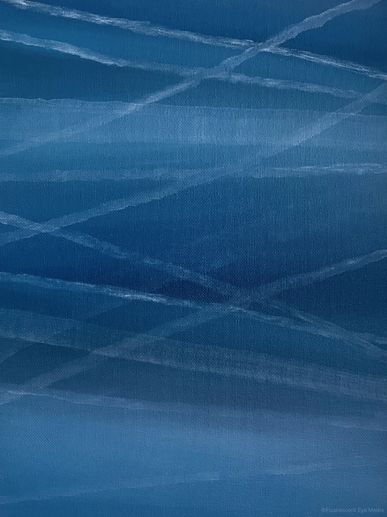 Blue sky with multiple white contrails crossing each other.